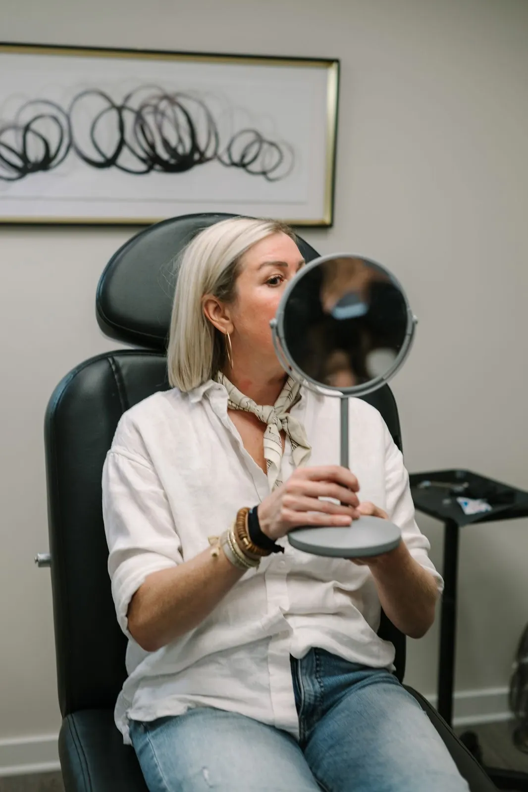 Woman viewing her face in the mirror | Arabella Medical Aesthetics | Knoxville, TX